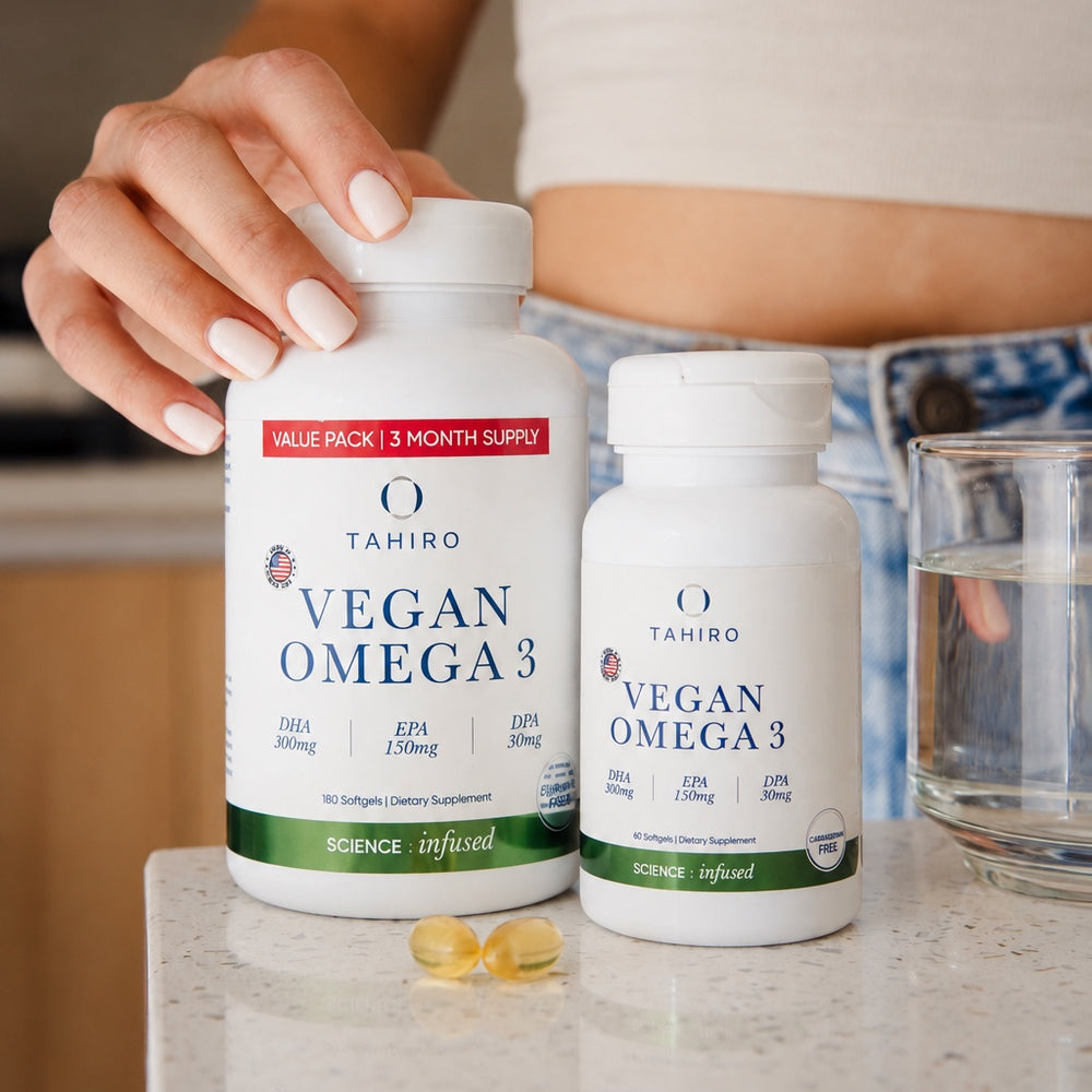 Hand holding the Tahiro Vegan Omega 3 three-month value pack next to a single bottle on a kitchen counter